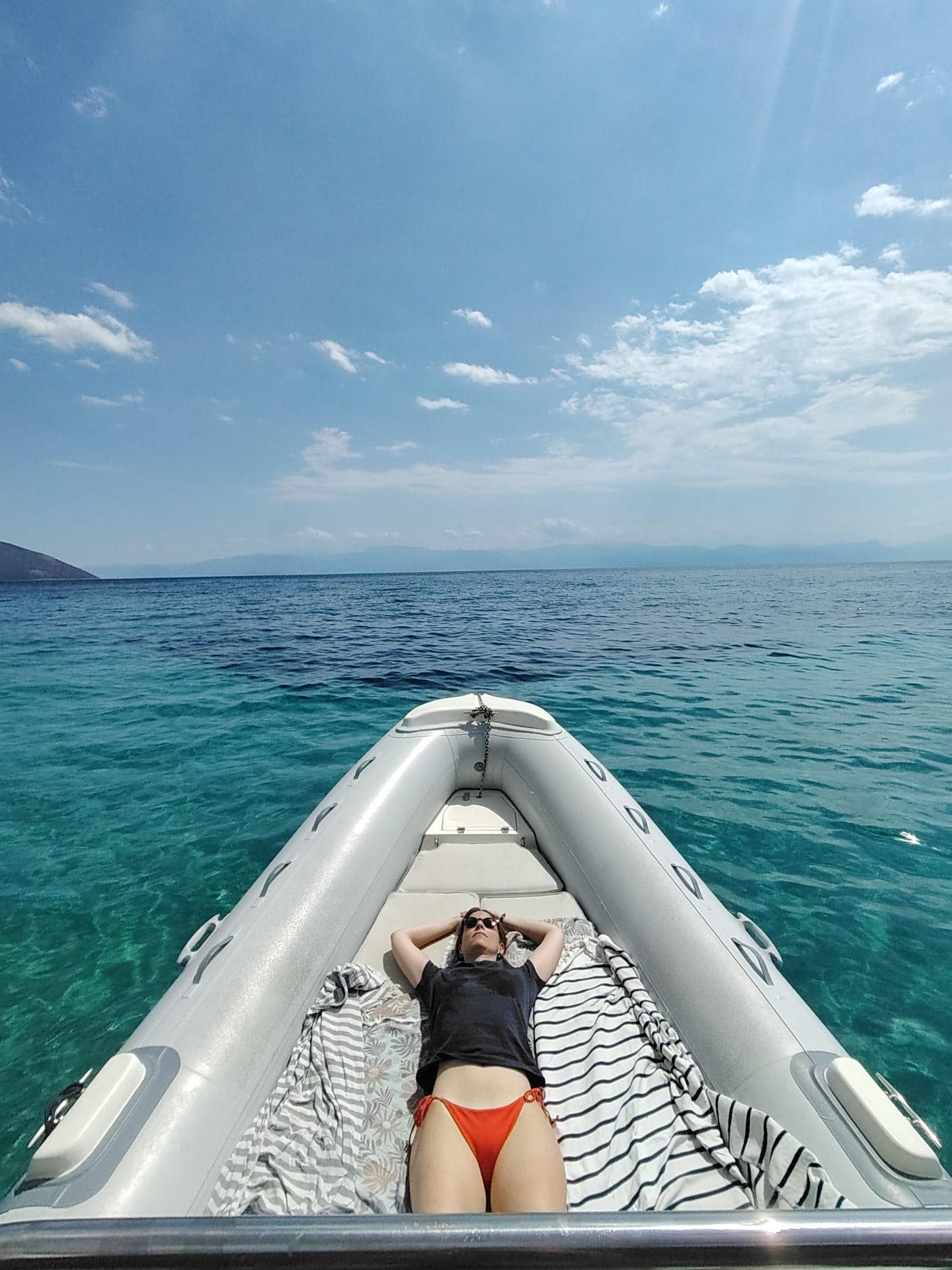 Guest sunbathing on the bow above turquoise water