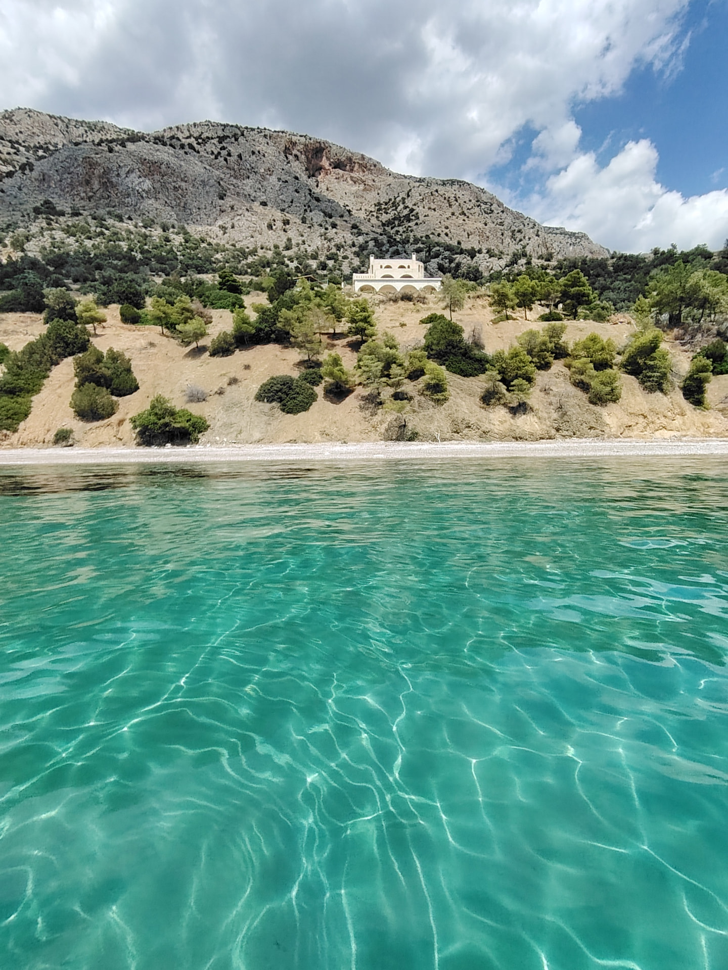Turquoise clear water in front of a coastal villa