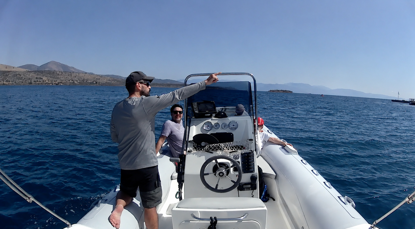 Skipper pointing toward the coastline while guests relax on the RIB