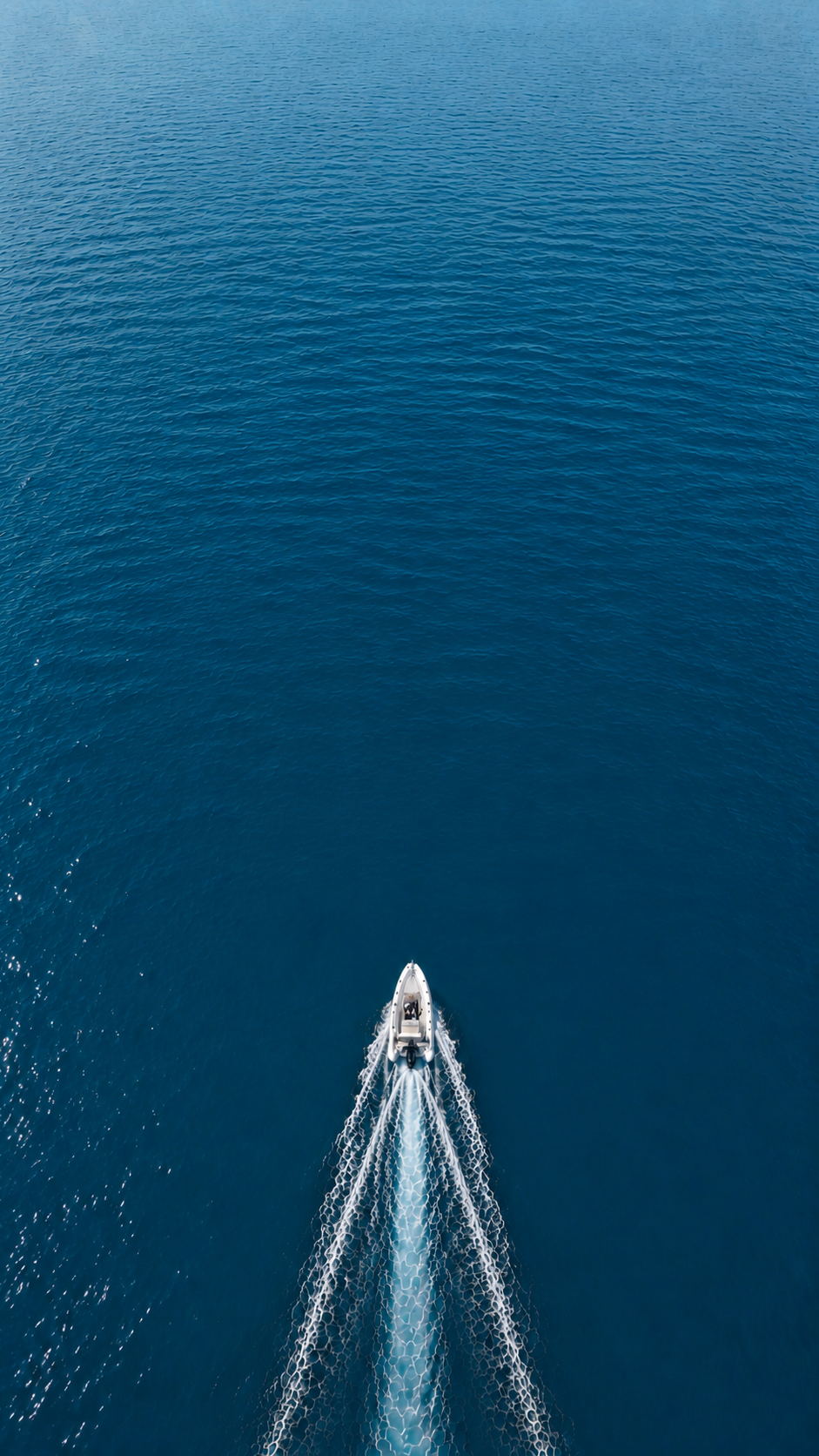 Aerial view of the RIB drawing a wake on deep blue sea