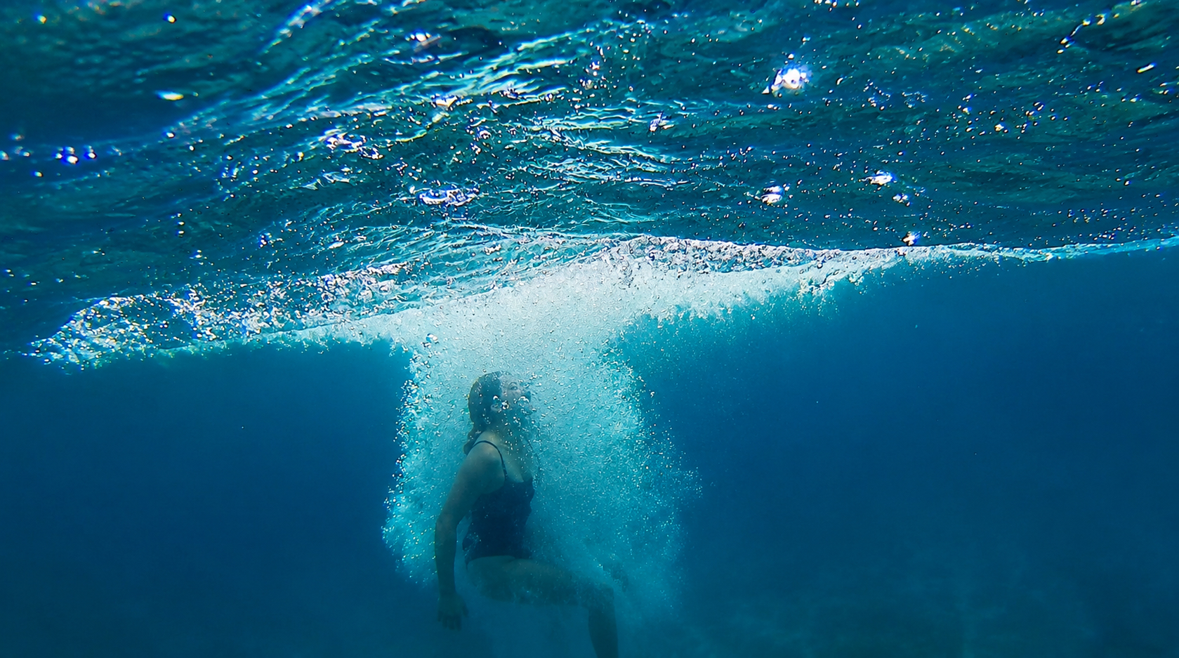 Swimmer diving beneath the surface in clear blue sea