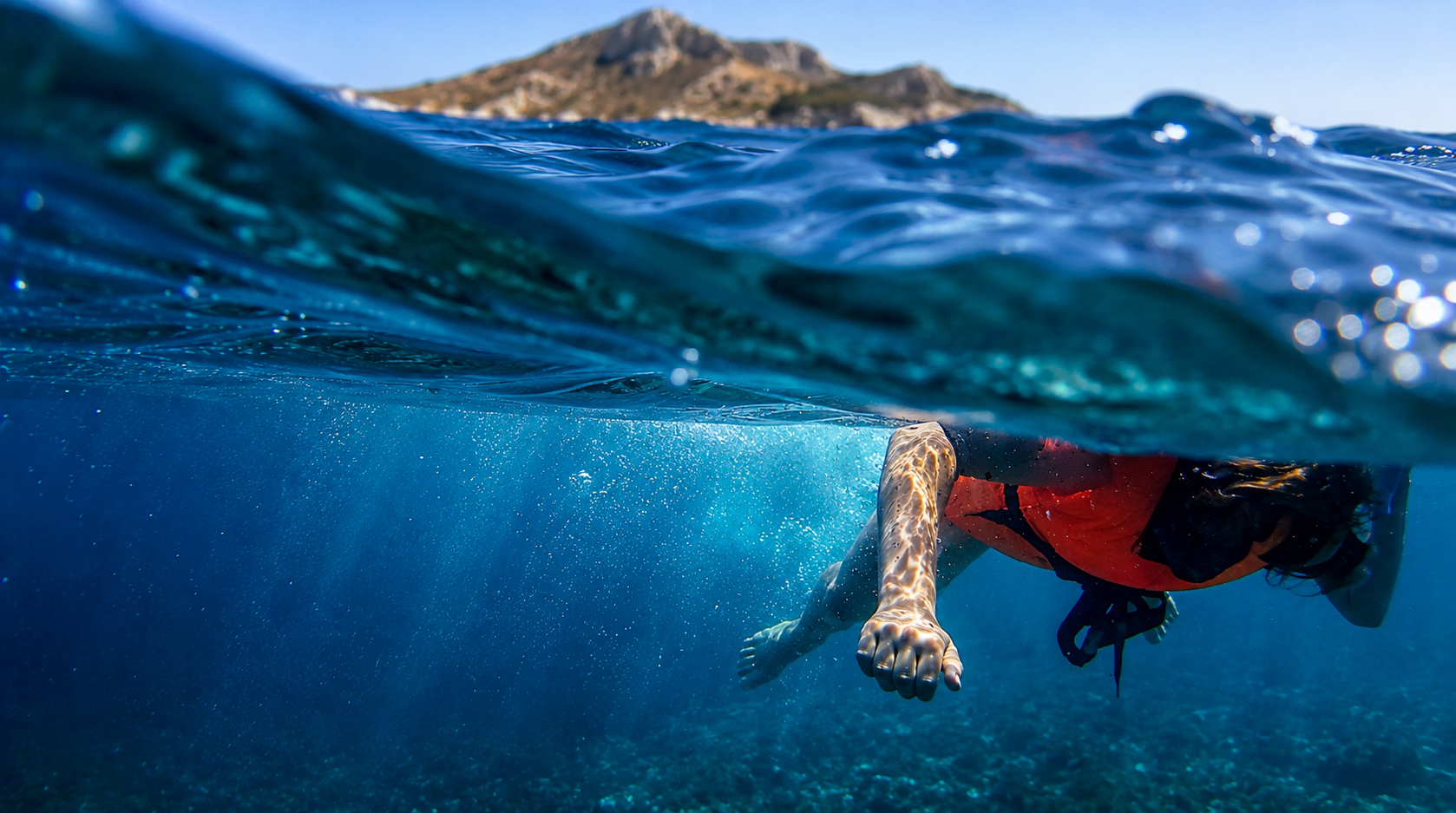 Split-level view of a swimmer with island in the background