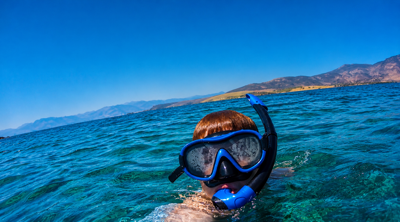 Young guest swimming with mask and snorkel in turquoise water