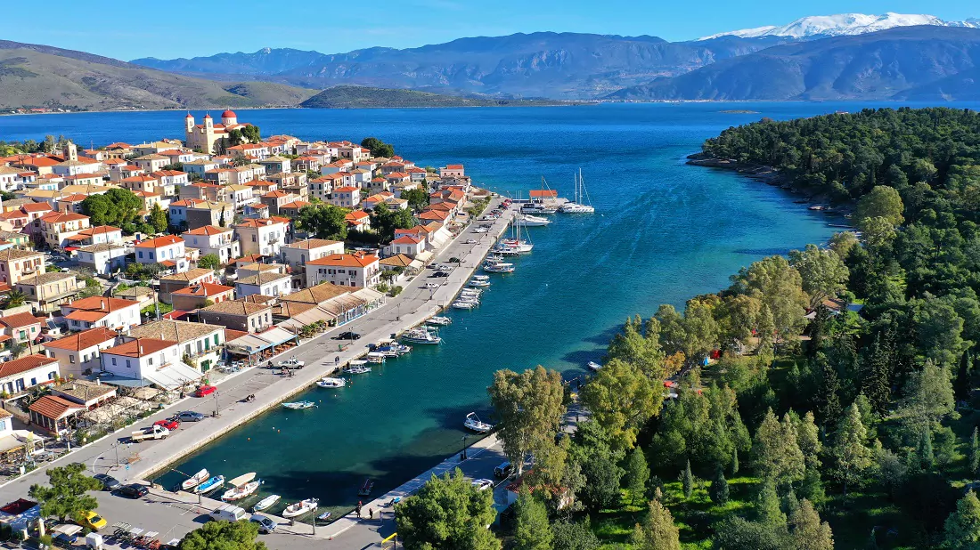 Aerial view of Galaxidi old harbour with stone houses, pine trees and the Gulf of Corinth
